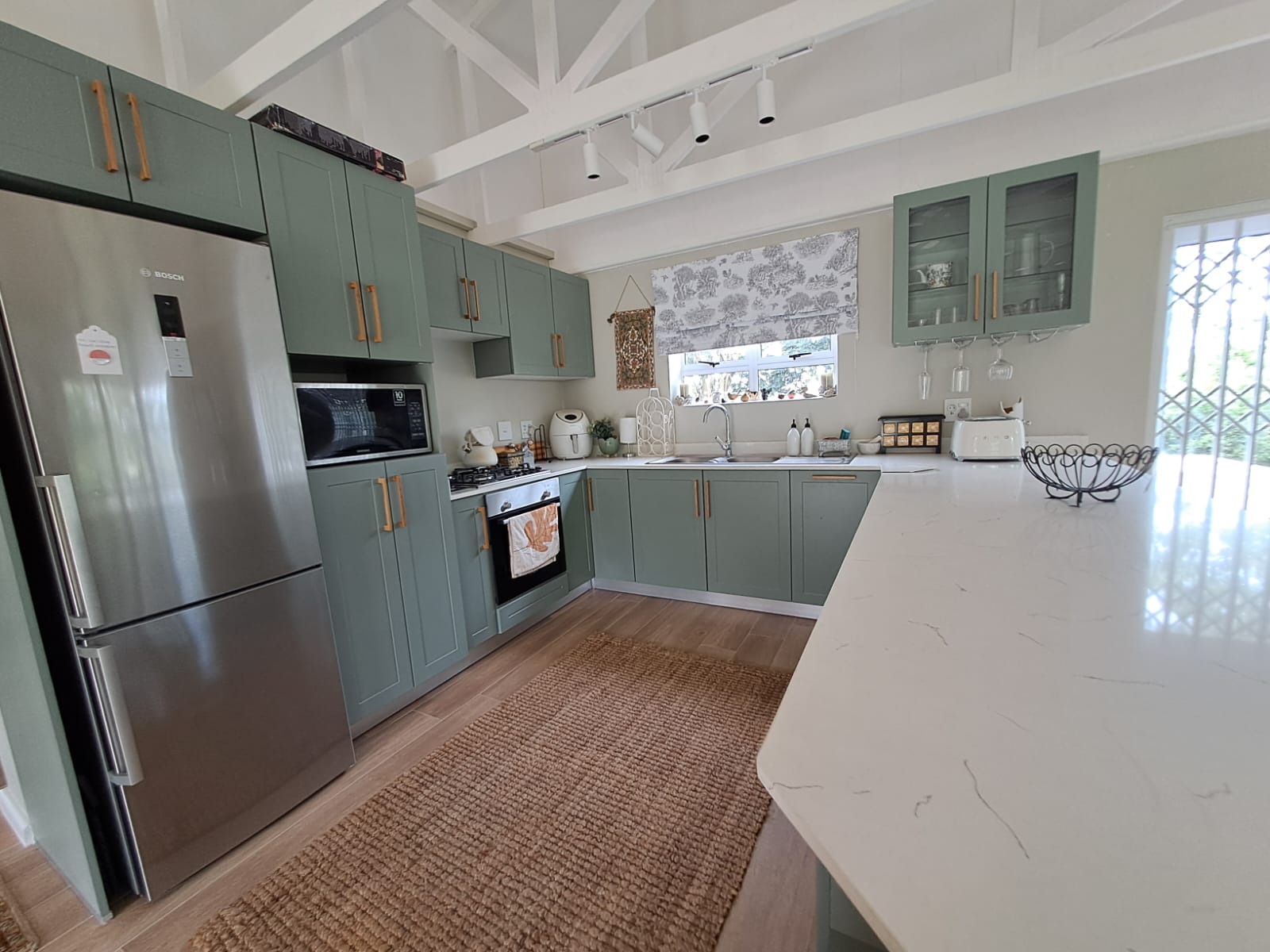 Kitchen with sage-green cabinetry and white stone countertops